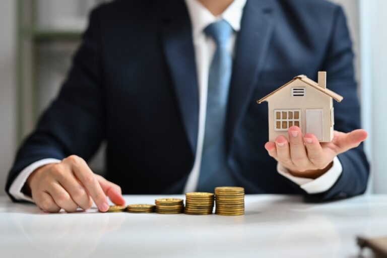 Main pointant un département sur une carte murale, chiffres immobiliers visibles en arrière-plan