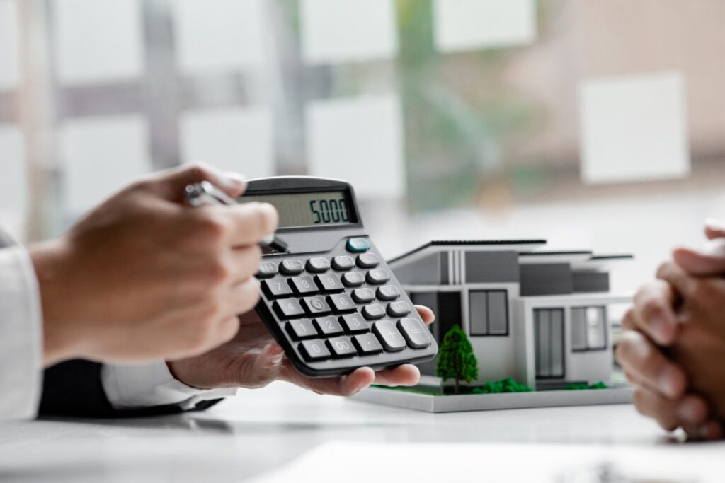 Une personne qui tient une calculatrice et montre le coût d'intérêt du prêt immobilier à l'emprunteur