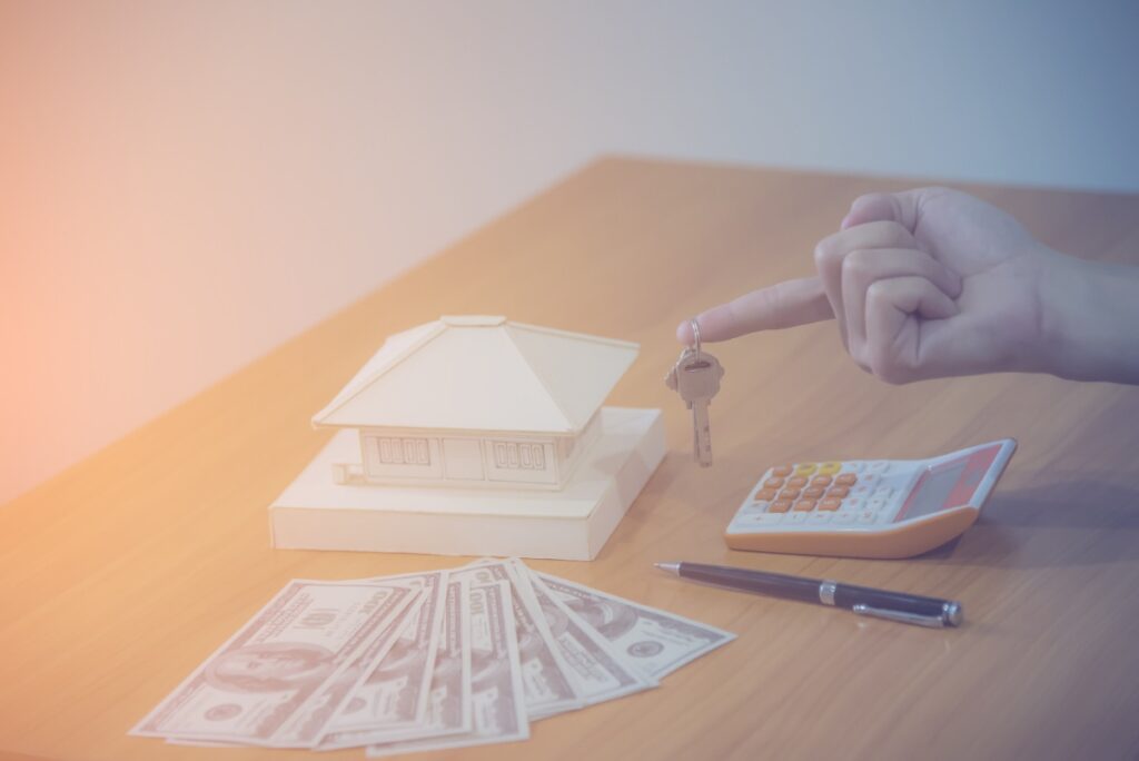 Une modèle de maison, une calculatrice, un stylo et des argents pour rembourser un prêt immobilier