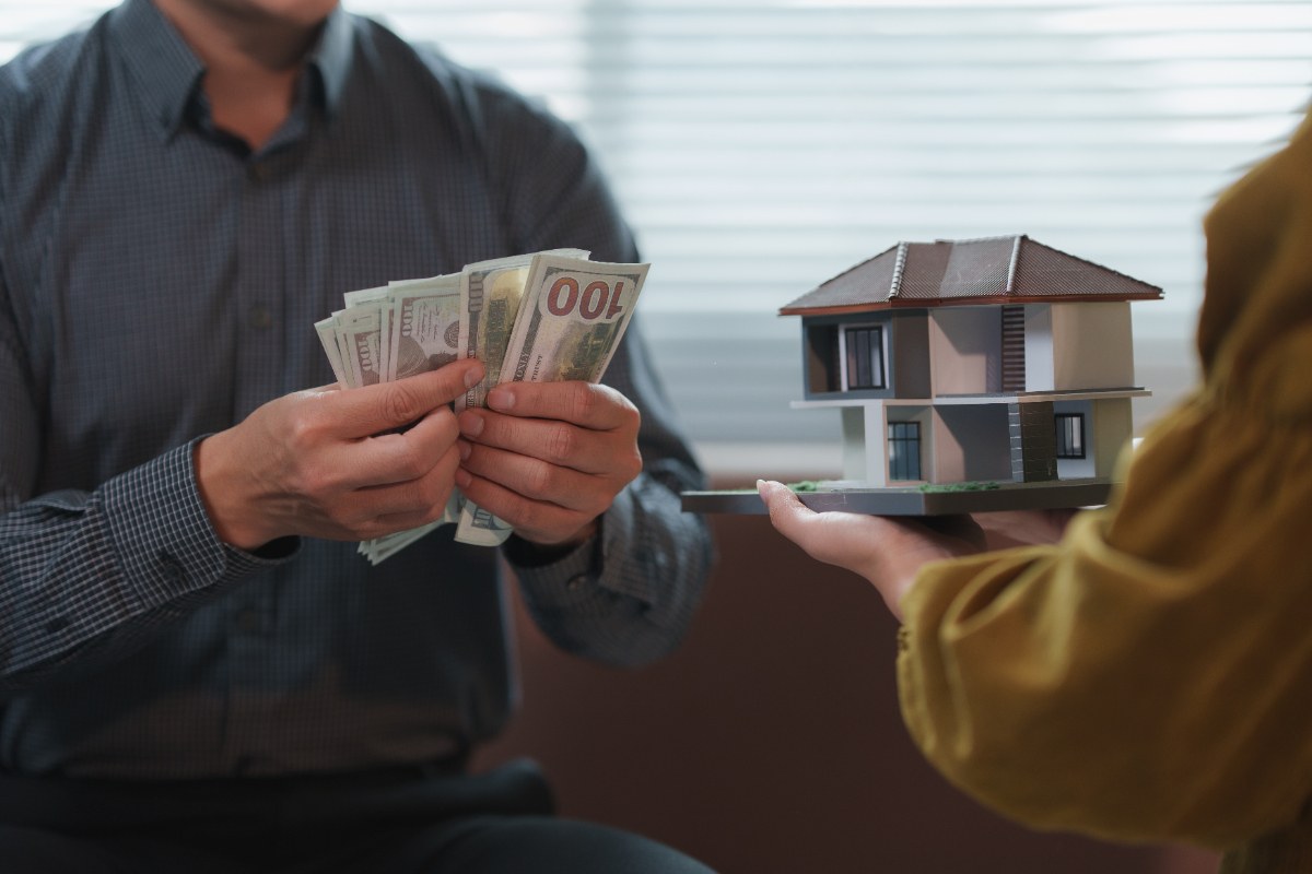 Une personne qui tient des monnaies pour le remboursement de son prêt immobilier