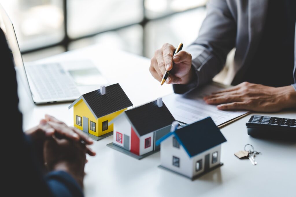 Un agent immobilier et une personne qui discute avec des maisons sur la table