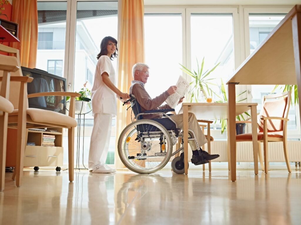 Une aide-soignante qui aide un homme âgé à lire un journal