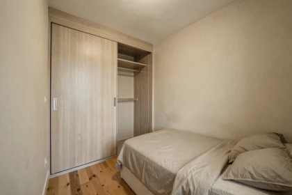 Petite chambre de moins de 9m² avec placard intégré à portes coulissantes occupant une partie de la surface au sol